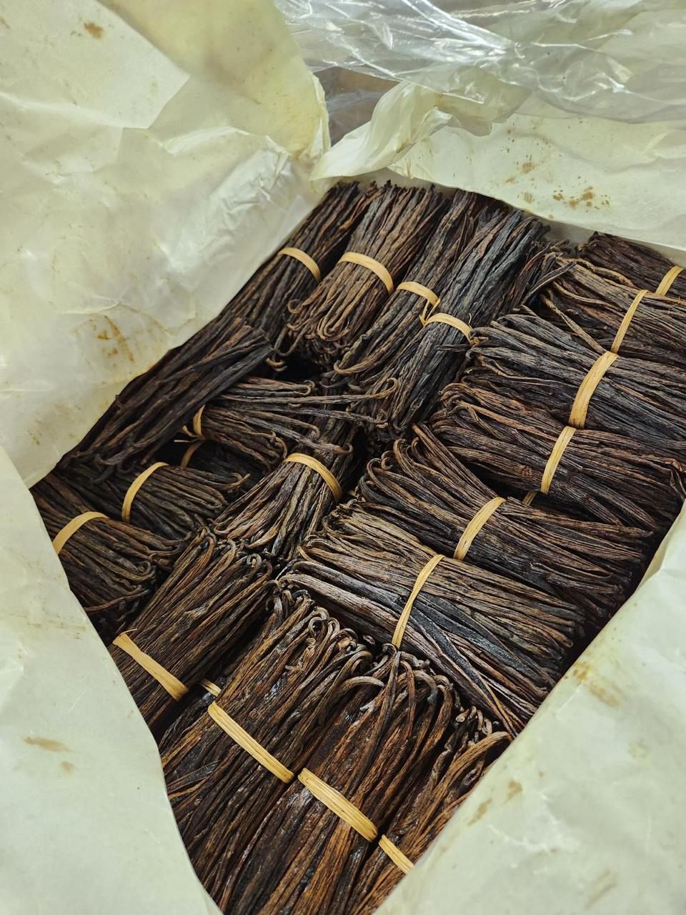 Vanilla beans tied into banded bundles and packed in paper inside an export carton